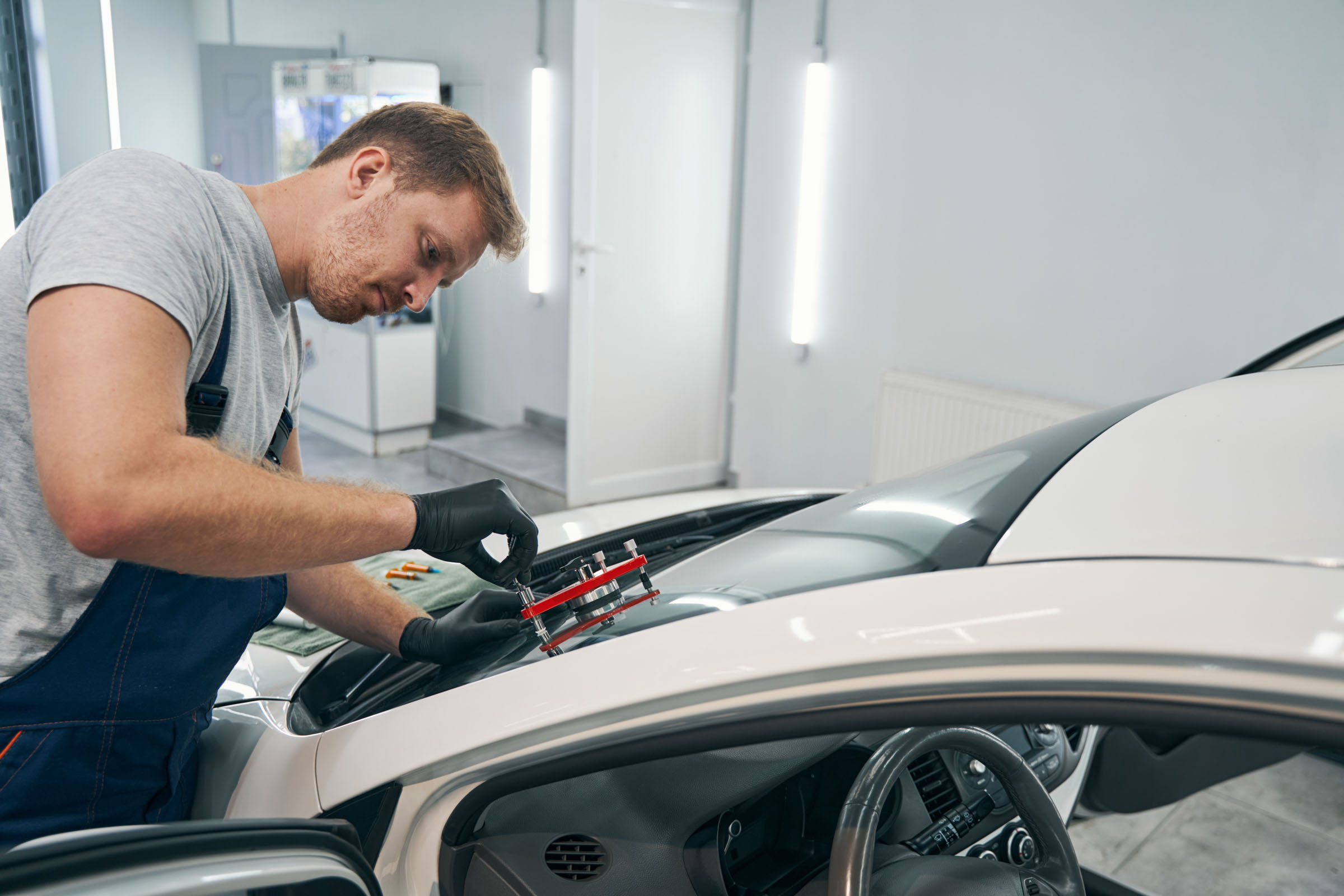 Closeup of man working with vacuum filler repair cracks in windshield