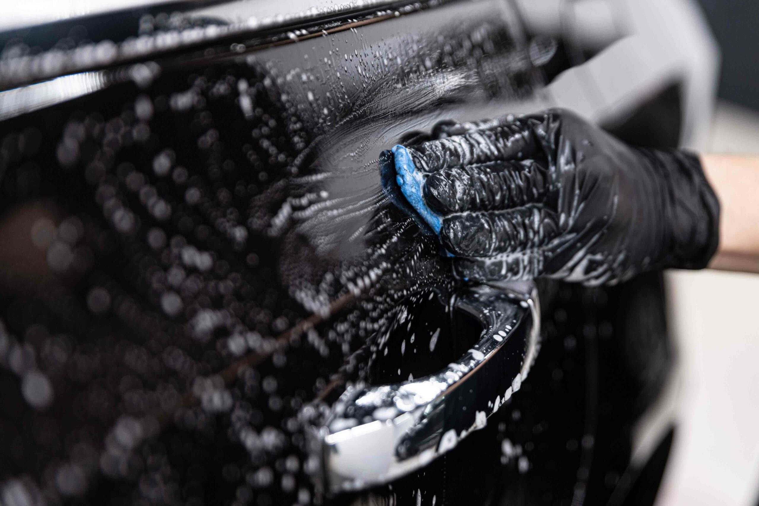 Worker washing car with sponge on a car wash, Manual car wash wi