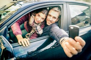 happy couple at car rent showing electronic key ready for the next road trip.jpg